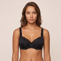 Woman wearing a black lace bra against a beige background