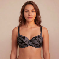 Woman wearing a black bralette against a beige background