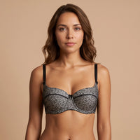 Woman wearing a black lace bra against a beige background