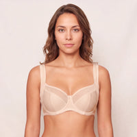 Woman wearing a beige bra against a plain background
